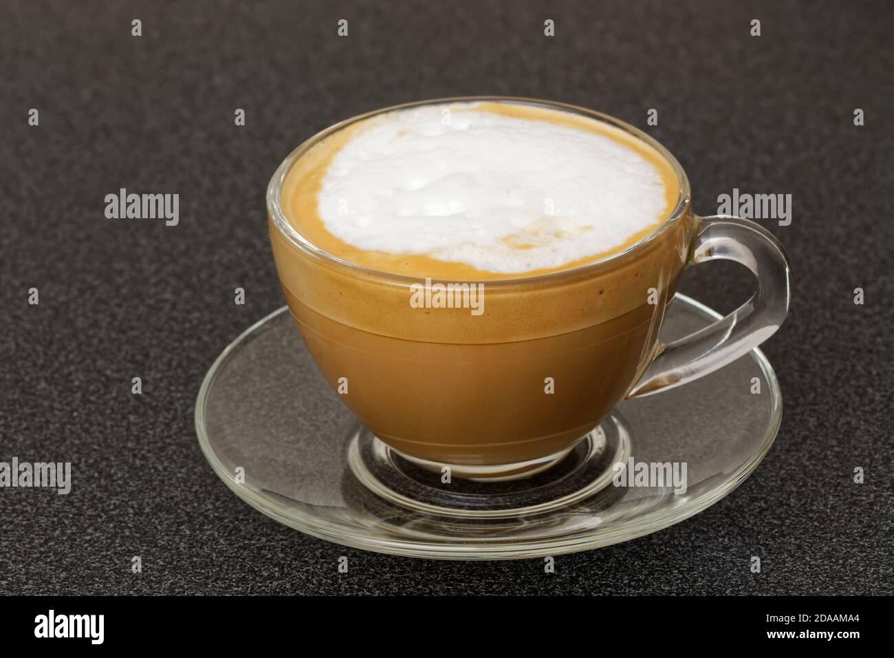 Transparente Tasse mit Cappuccino auf dunklem Tisch Stockfoto