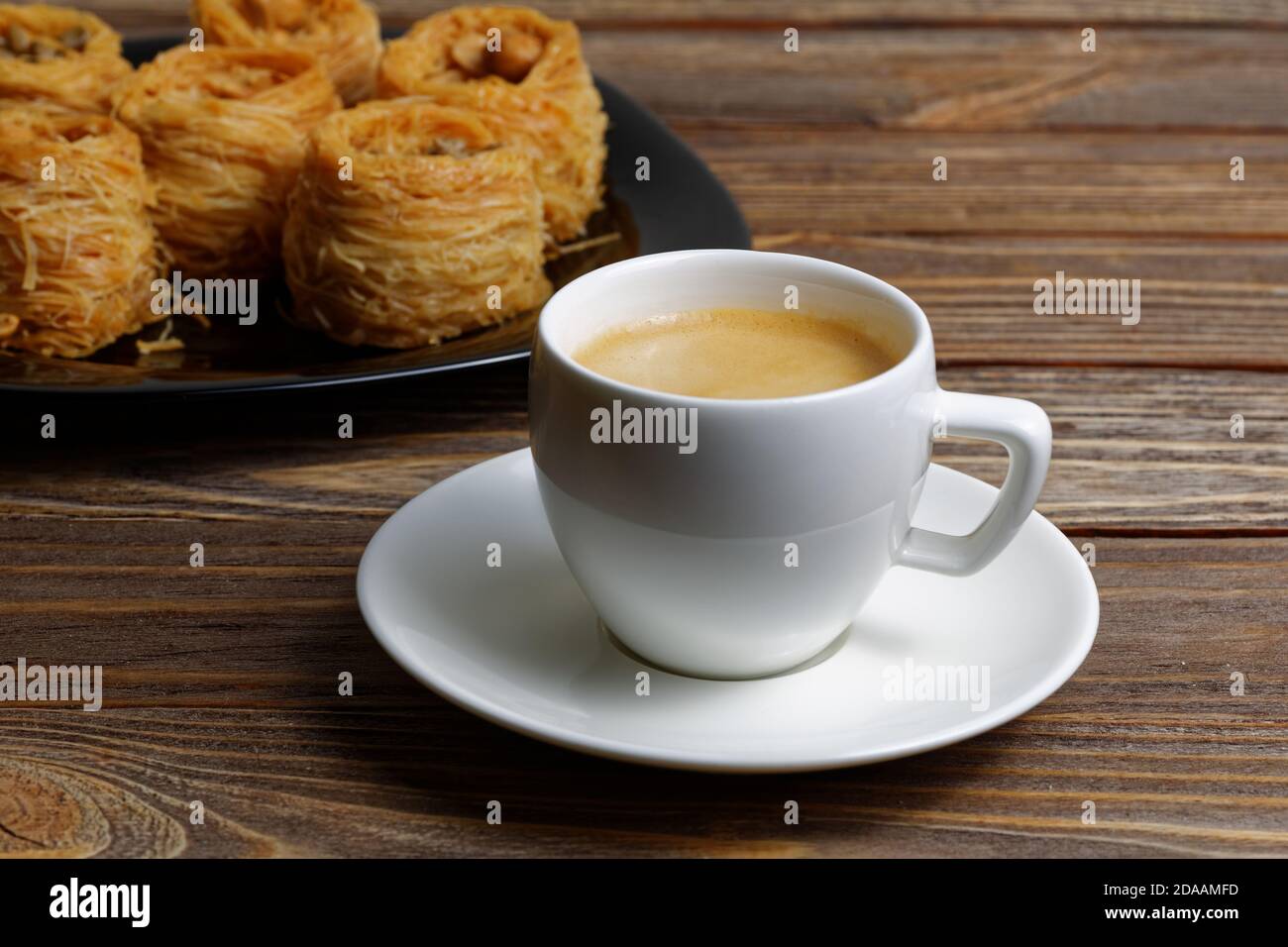Tasse Kaffee Espresso auf Holztisch und östlichen Süßigkeiten auf verschwommenem Backgrpund. Geringer Fokus. Stockfoto