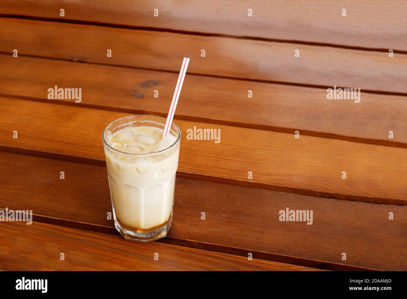 Eiskaffee in einem hohen Glas auf Holztisch. Copyspace. Stockfoto