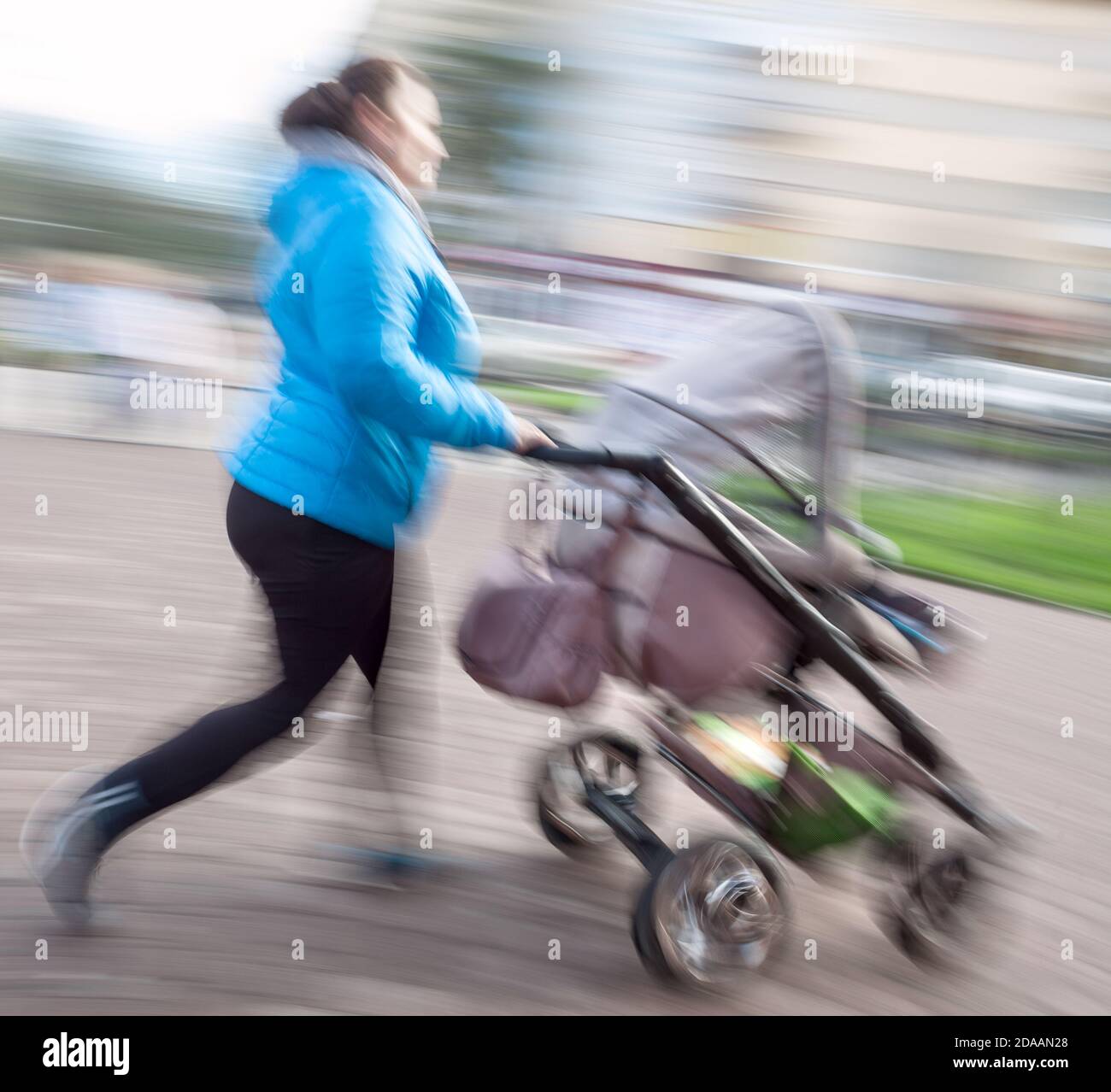 Mutter mit kleinen Kindern und einem Kinderwagen, der die Straße entlang läuft. Absichtliche Bewegungsunschärfe Stockfoto