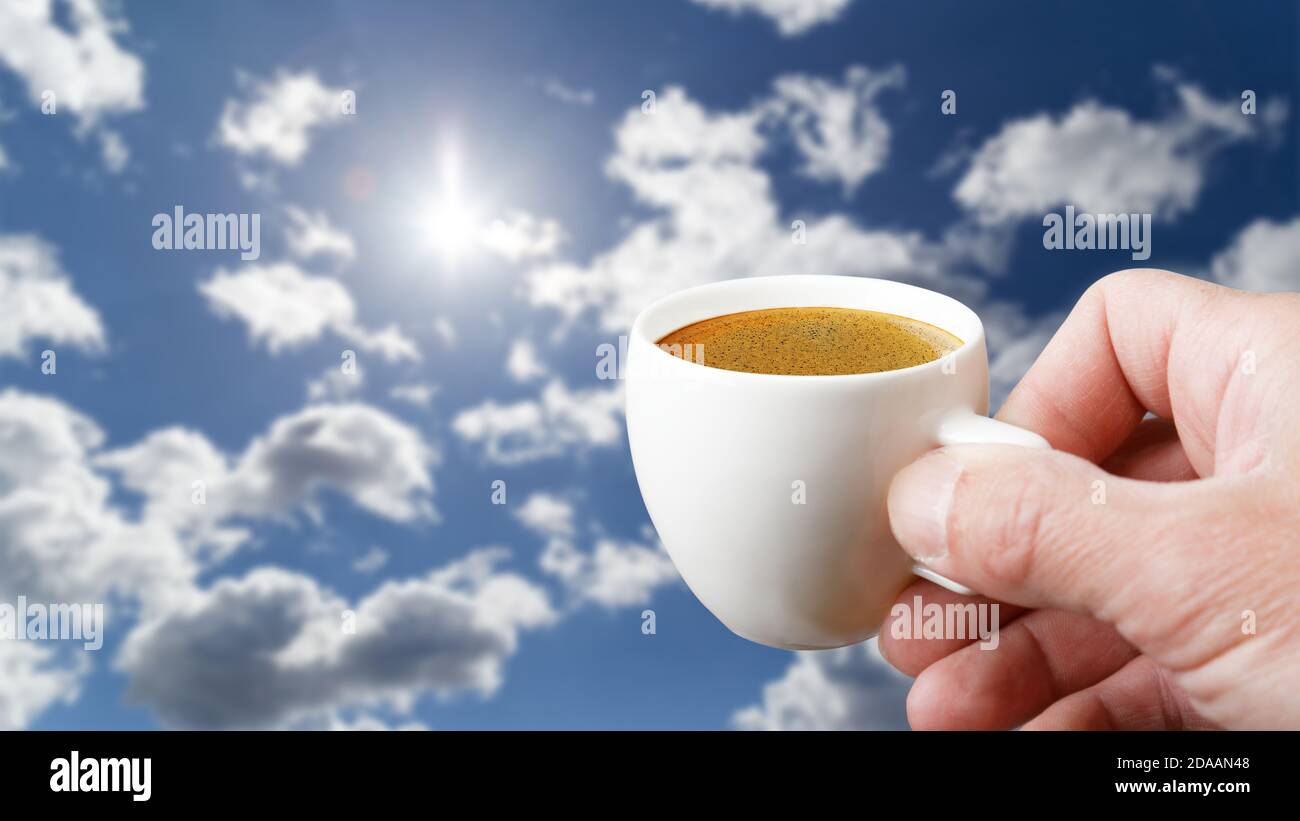 Menschen Hände halten weiße Tasse Kaffee gegen blau wolkigen Himmel. Sommerkonzept mit Copyspase. Stockfoto