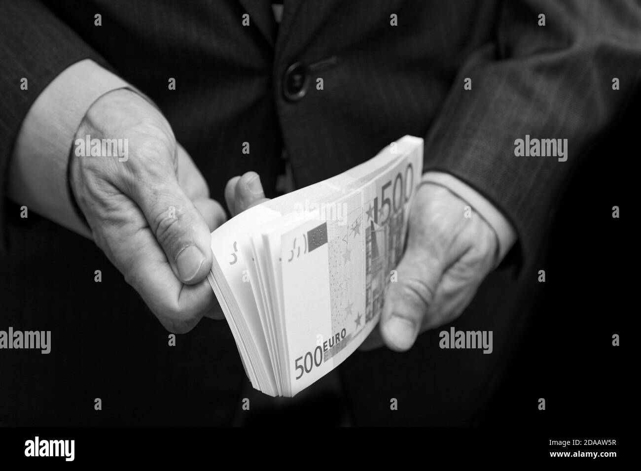Ein Mann zählt das Geld in einem Geldbündel von 500 Euro. Geringer Fokus. Schwarz-Weiß-Geschäfts- oder Finanzkonzept. Stockfoto