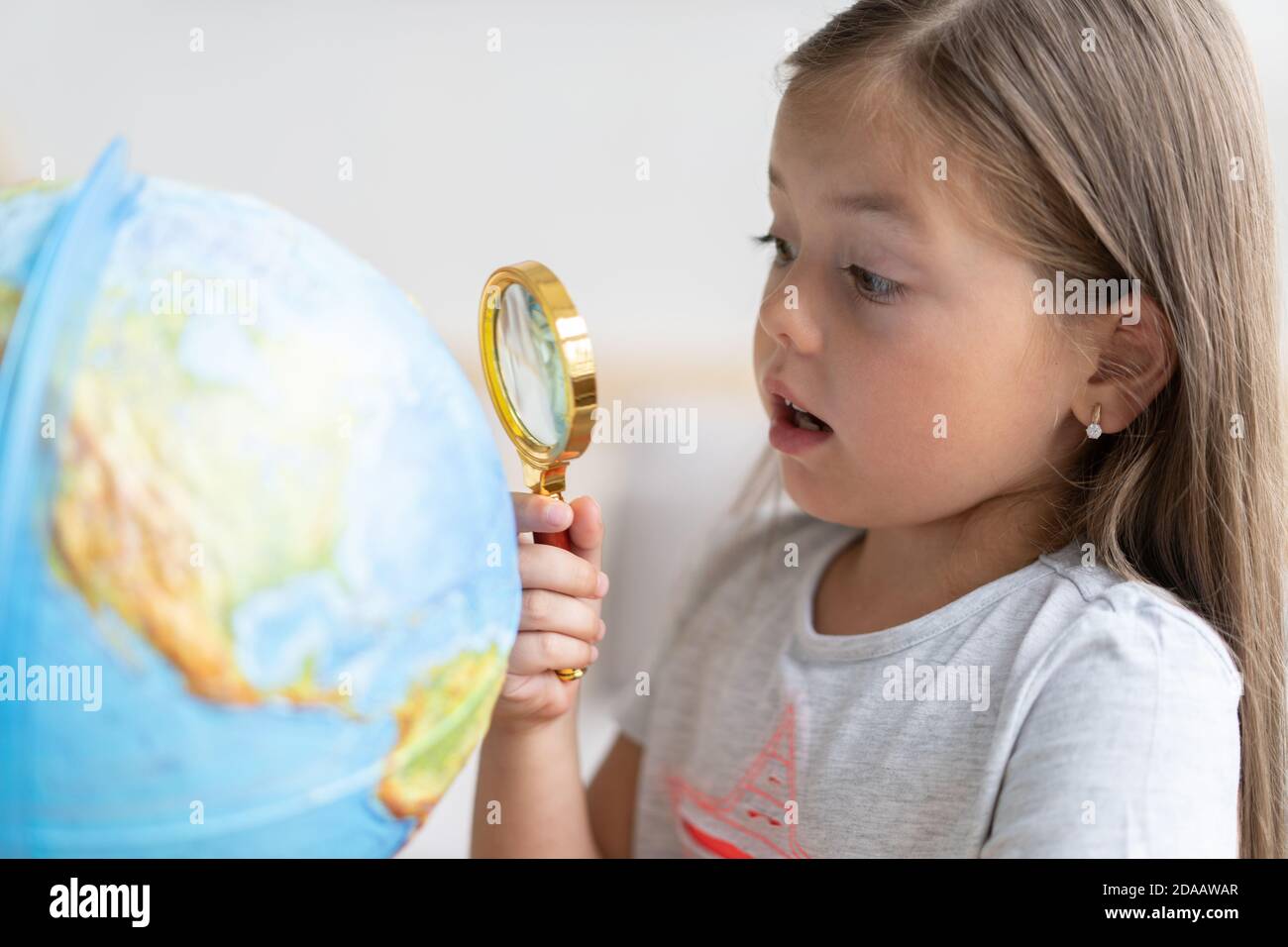 Bildung und Schulkonzept. Kind Mädchen zeigt auf den Globus. Stockfoto