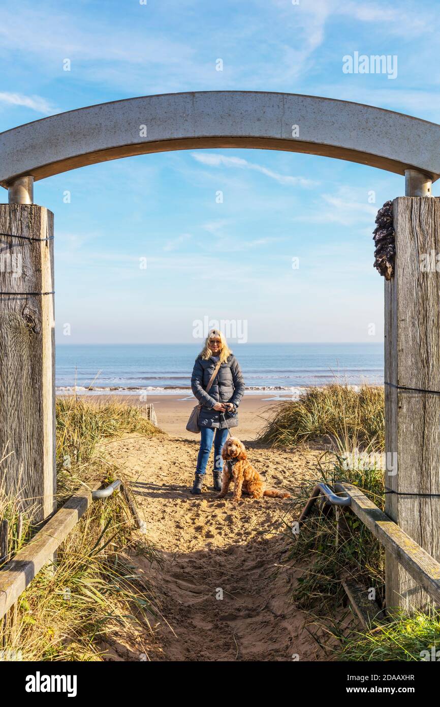 Hundewanderung am Strand, Wanderhund am Strand, Mablethorpe, Lincolnshire, UK, Frau mit Hund, cockapoo, rote cockapoo, posieren mit Hund, Hundewanderung, Hund, Strand, Stockfoto