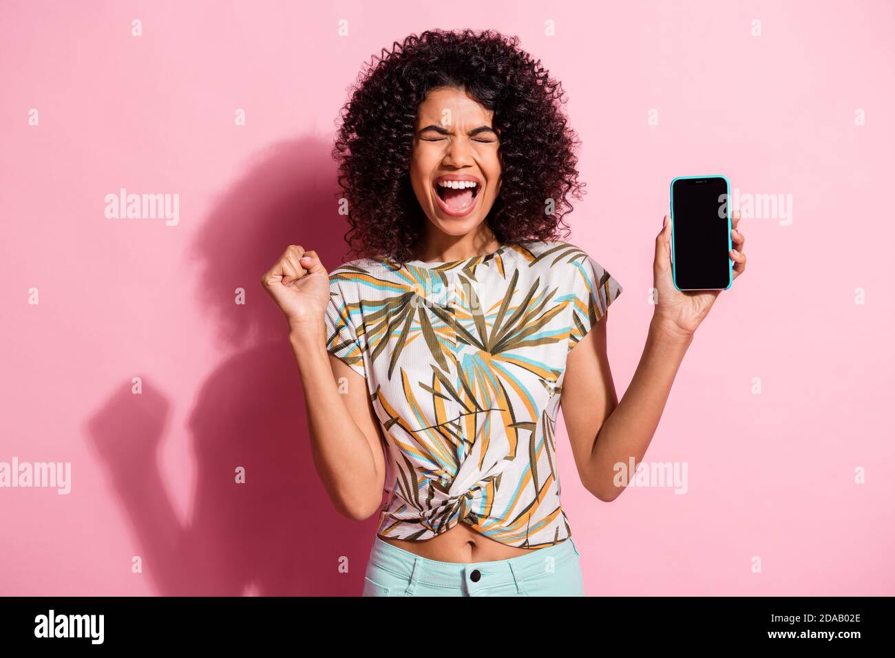 Portrait Foto von schreienden schwarzen Haut lockig Frau halten Smartphone Mit Copyspace isoliert auf pastellrosa Hintergrund Stockfoto
