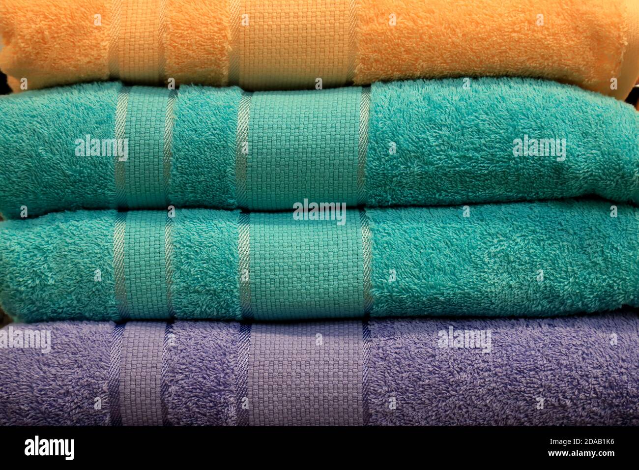 Ein Stapel Frottee Handtücher liegt auf einem Regal im Bad, Spa, Kleiderschrank, Wäscherei, Shop. Hygieneartikel, weiche Badetücher im Supermarkt in grün Stockfoto