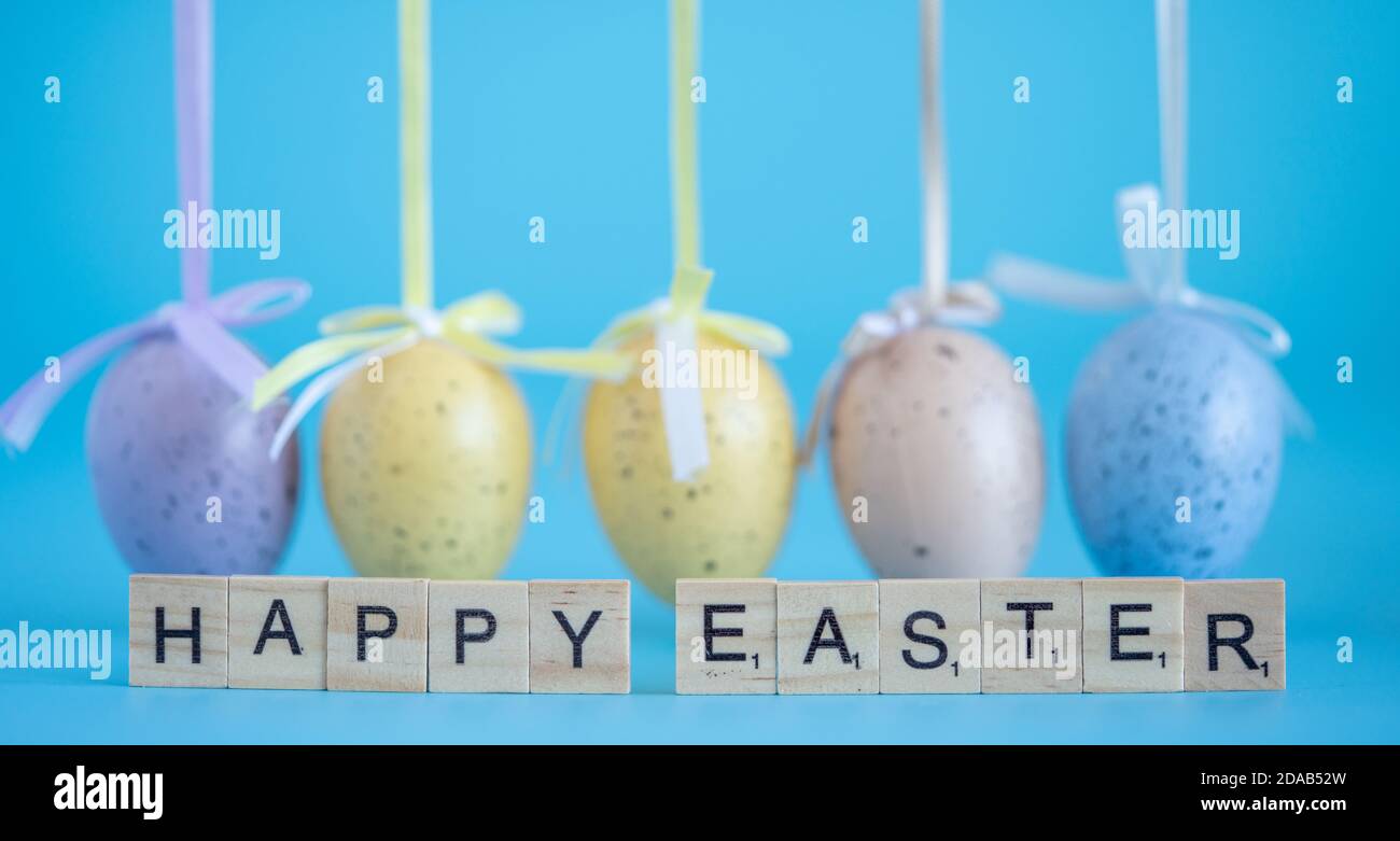 Fröhlicher Ostertext aus Holzbuchstaben auf türkisfarbenem Hintergrund. Stockfoto