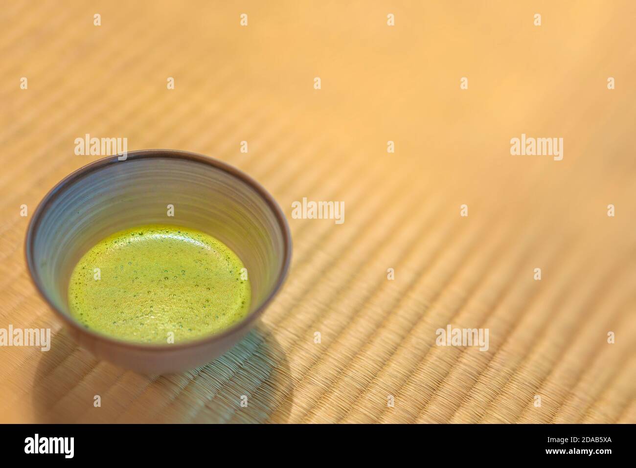 Hintergrund einer Keramik-Ware Chawan Cup von japanischen Matcha Grüner Tee auf einer Tatami-Matte mit gewebten weich bedeckt Strohhalm im traditionellen japanischen Stil Stockfoto
