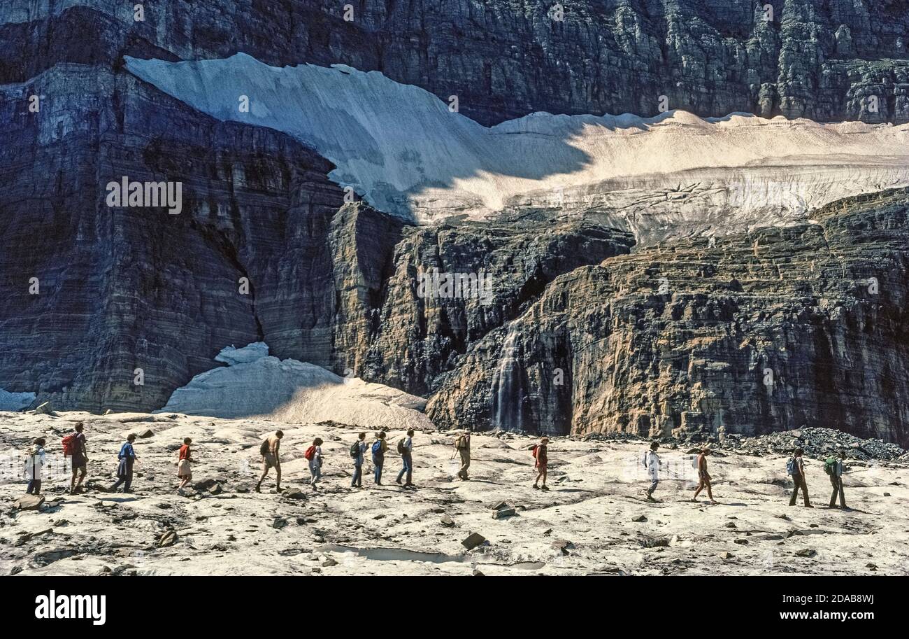 Eine Reihe von Wanderern auf einer von Rangern geführten Tour durchquert einen eisigen Rest des sich zurückziehenden Grinnell Glacier, eine langjährige Attraktion im Glacier National Park, einem riesigen Wildnisreservat im Nordwesten von Montana, USA. Der Gletscher wurde nach George Bird Grinnell benannt, einem frühen Naturschützer, der 1885 das Eisfeld entdeckte und 1910 dazu verhalf, die unberührte Region als 10. Nationalpark Amerikas zu etablieren. Leider haben die zahlreichen Gletscher, nach denen der Park benannt ist, im Laufe der Jahre unter dem Klimawandel gelitten. Von schätzungsweise 146 Gletschern in der Mitte des 19. Jahrhunderts sind nur noch 26 benannte Gletscher übrig geblieben. Stockfoto