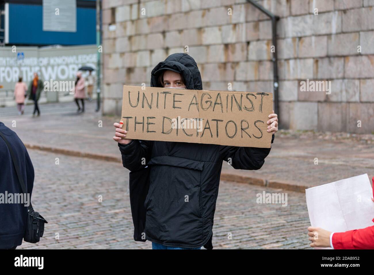 Demonstrator mit einem Schild aus Pappe, auf dem steht: "Vereinigt euch gegen die Diktatoren" auf dem Senatsplatz in Helsinki, Finnland Stockfoto