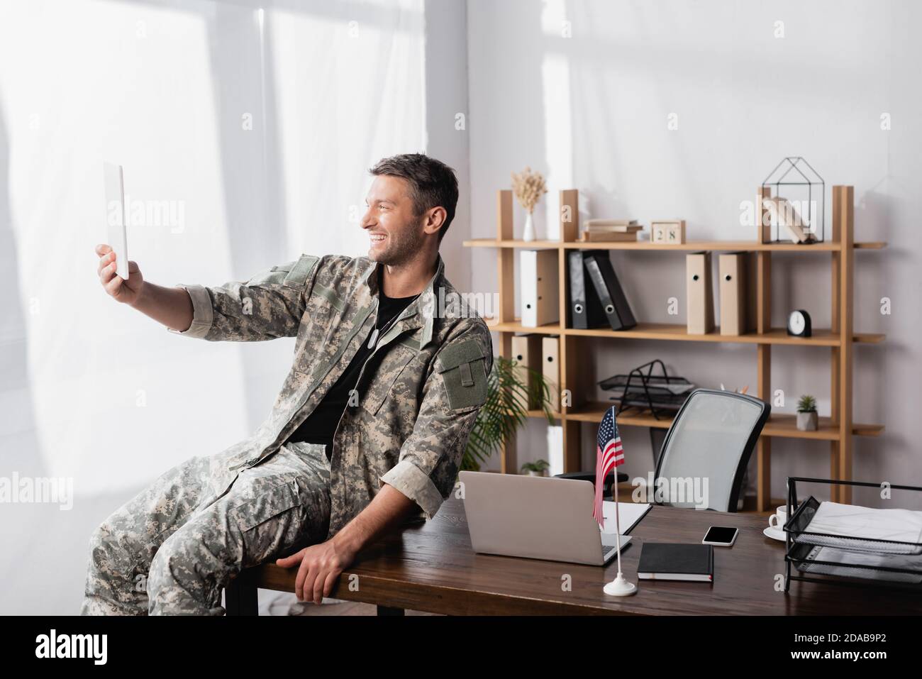 Glücklicher Soldat in Militäruniform mit digitalen Tablet beim Haben Video-Chat im Büro Stockfoto