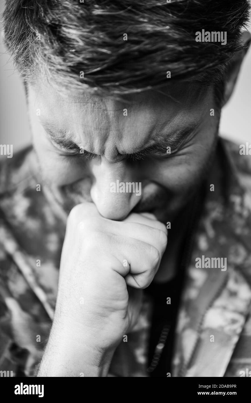 Soldat in Militäruniform weinend mit geschlossenen Augen, monochrom Stockfoto