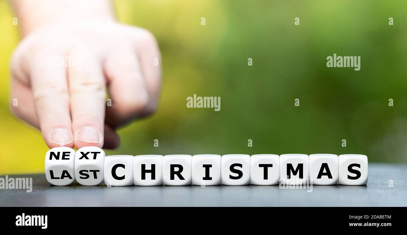 Hand dreht Würfel und ändert den Ausdruck "Last Christmas" zu "Next Christmas". Stockfoto