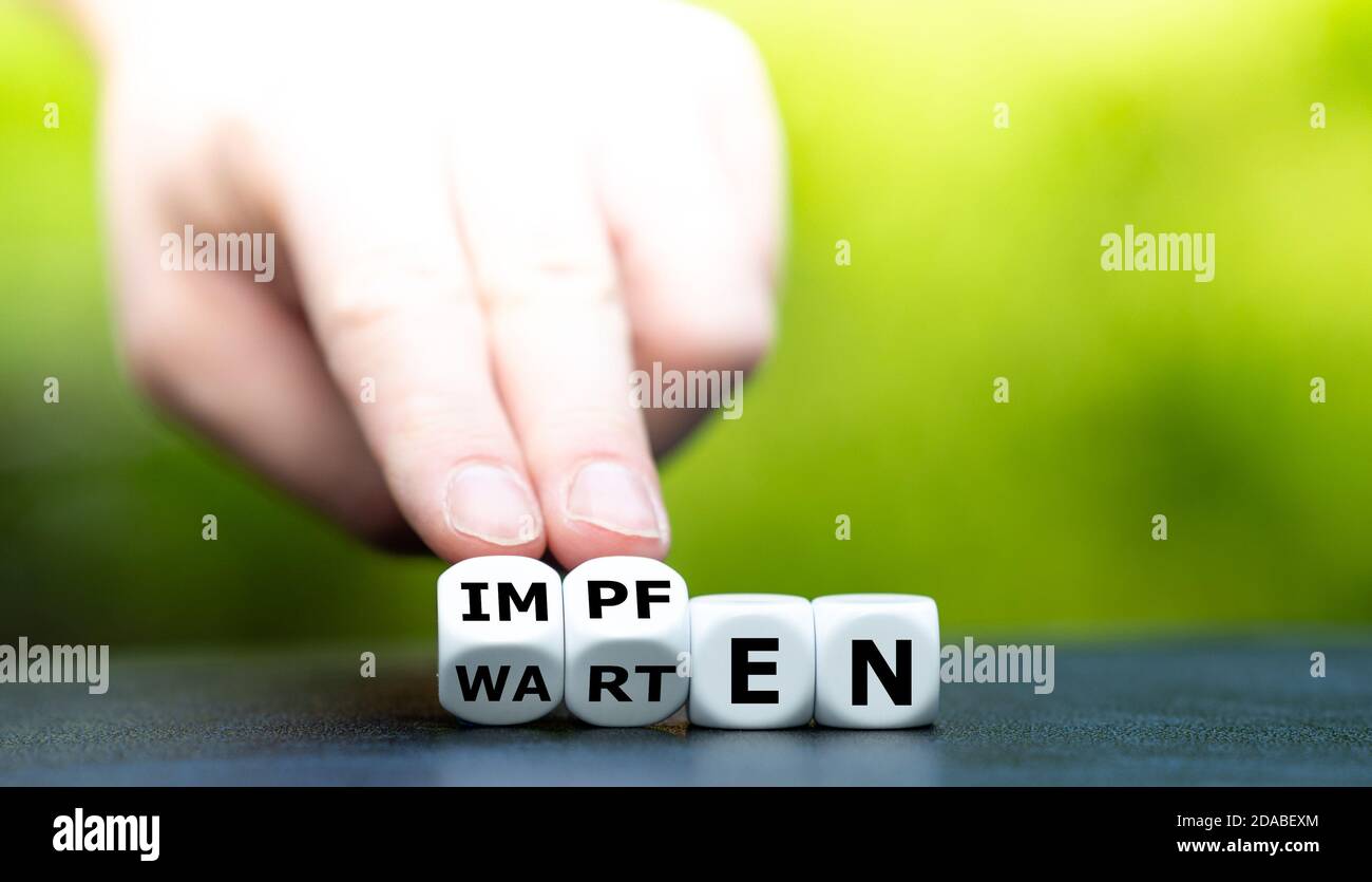 Symbol für einen entwickelten Corona-Impfstoff. Die Hand dreht Würfel und ändert das deutsche Wort 'warten' in 'impfen' (impfen). Stockfoto Symbol für einen entwickelten Corona-Impfstoff. Die Hand dreht Würfel und ändert das deutsche Wort 'warten' in 'impfen' (impfen). Stockfoto