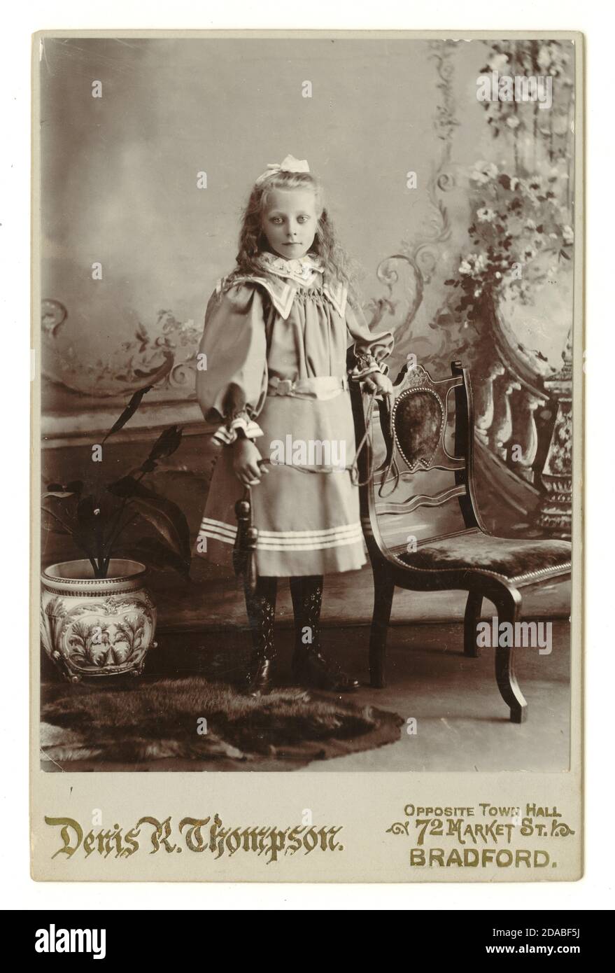 Original viktorianische Kabinettkarte von hübschen jungen Mädchen, trägt ein modisches Kleid mit Puffärmeln, hält Kegeln, Bradford, England, U.K. um 1897 Stockfoto