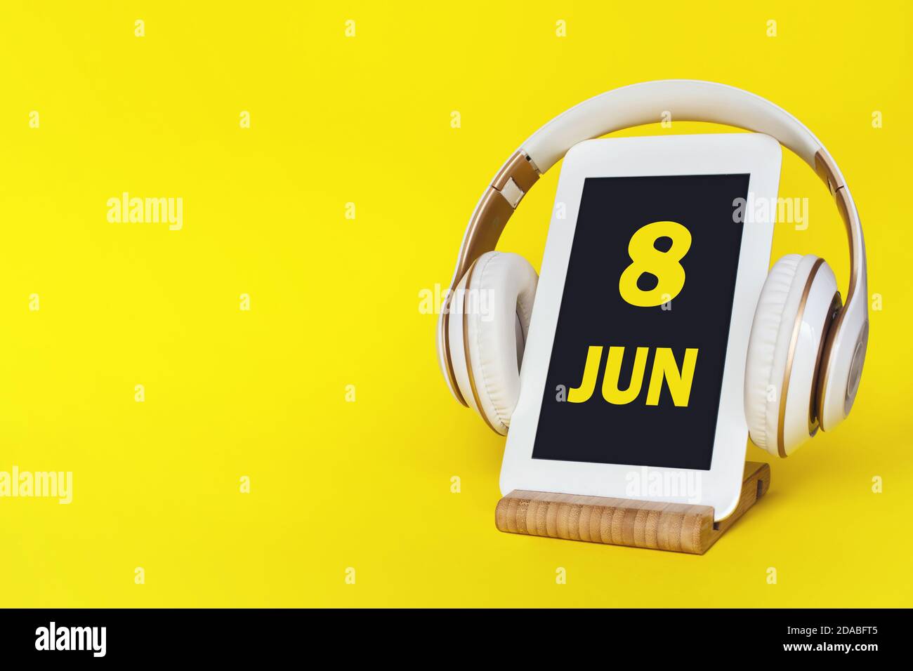 Juni. Tag 8 des Monats, Kalenderdatum. Elegante Kopfhörer und modernes Tablet auf gelbem Hintergrund. Leerzeichen für Text. Bildung, Technologie, Lifestyle. Stockfoto