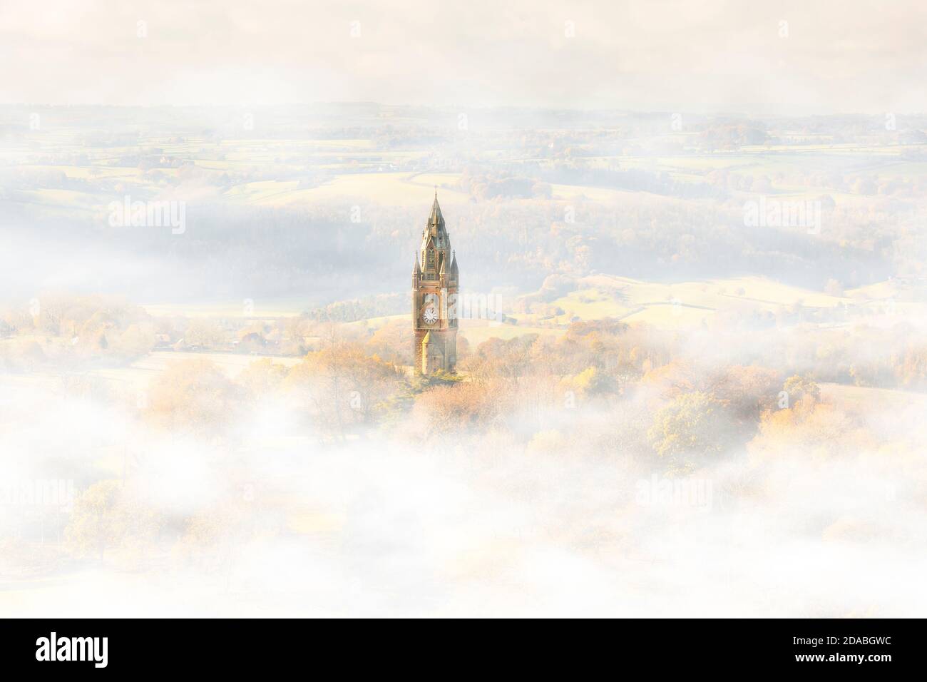 Abberley Uhrturm (Mini Big Ben) platzt durch den Nebel, während die aufgehende Herbstsonne durch das Tal strömt und den Uhrenturm erleuchtet. Stockfoto