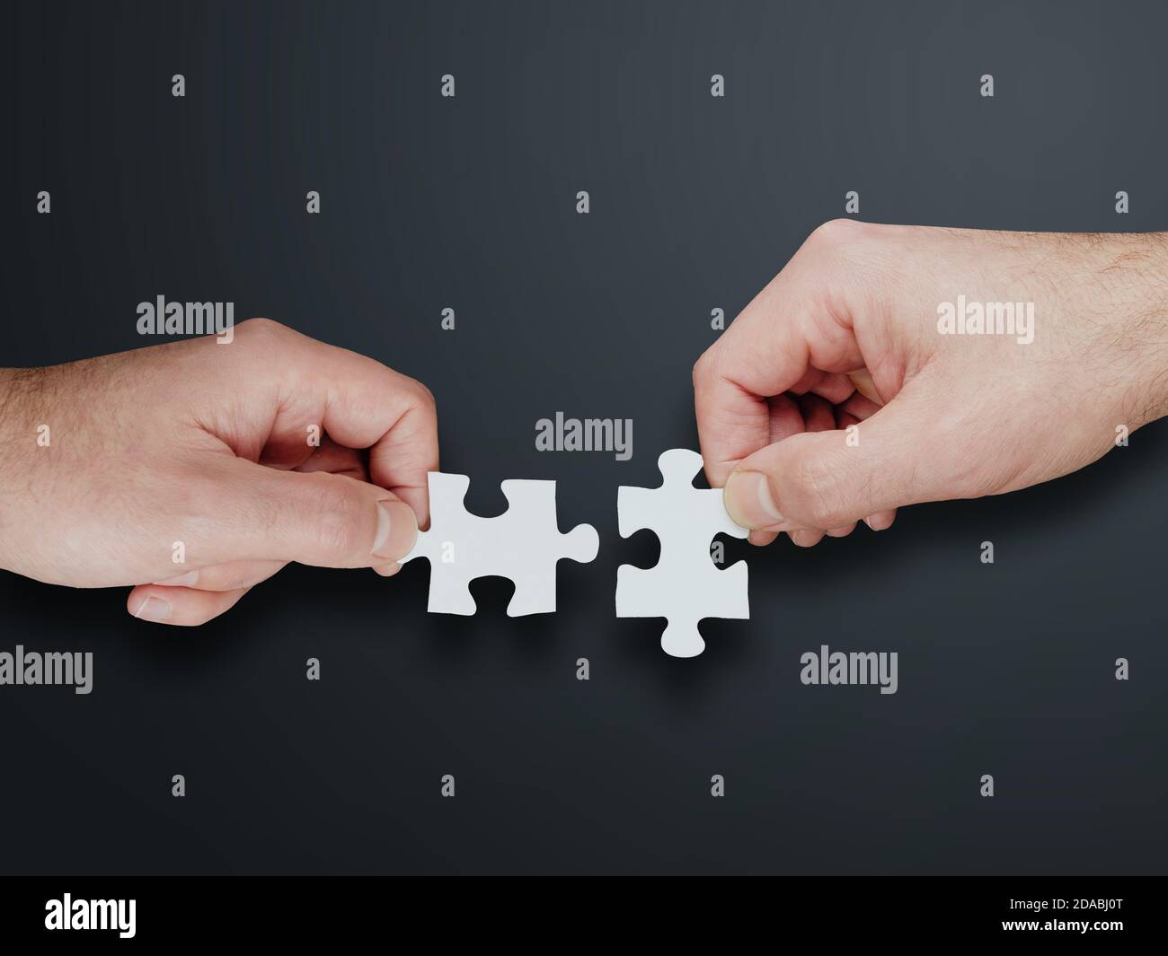 Hände von zwei Personen, die zwei Puzzleteile zusammenfügen, Lösungen finden und Teamwork-Konzept Stockfoto