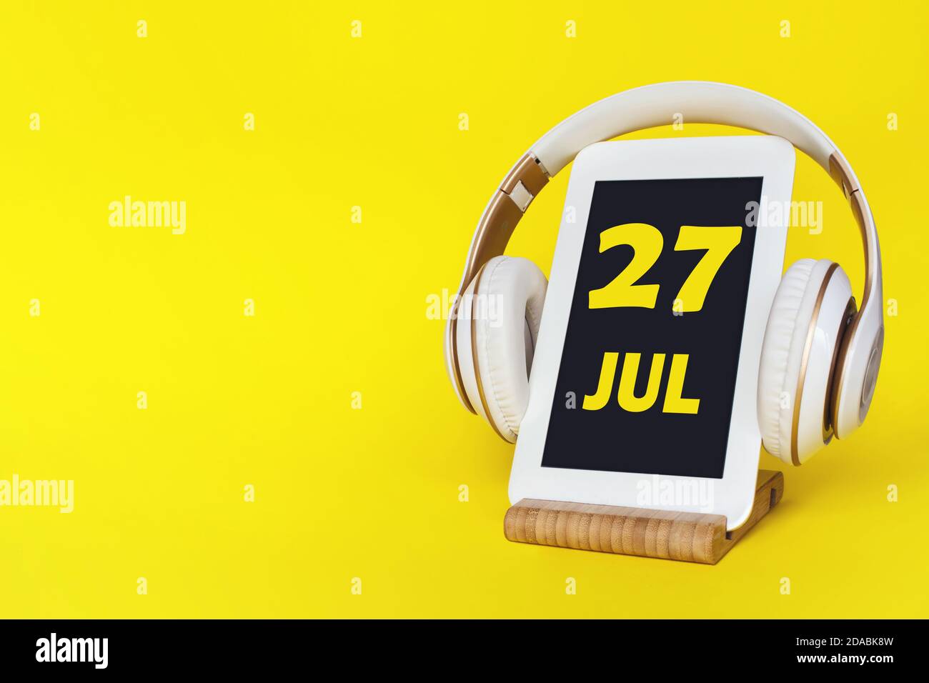 Juli. Tag 27 des Monats, Kalenderdatum. Elegante Kopfhörer und modernes Tablet auf gelbem Hintergrund. Leerzeichen für Text. Bildung, Technologie, Lifestyle Stockfoto