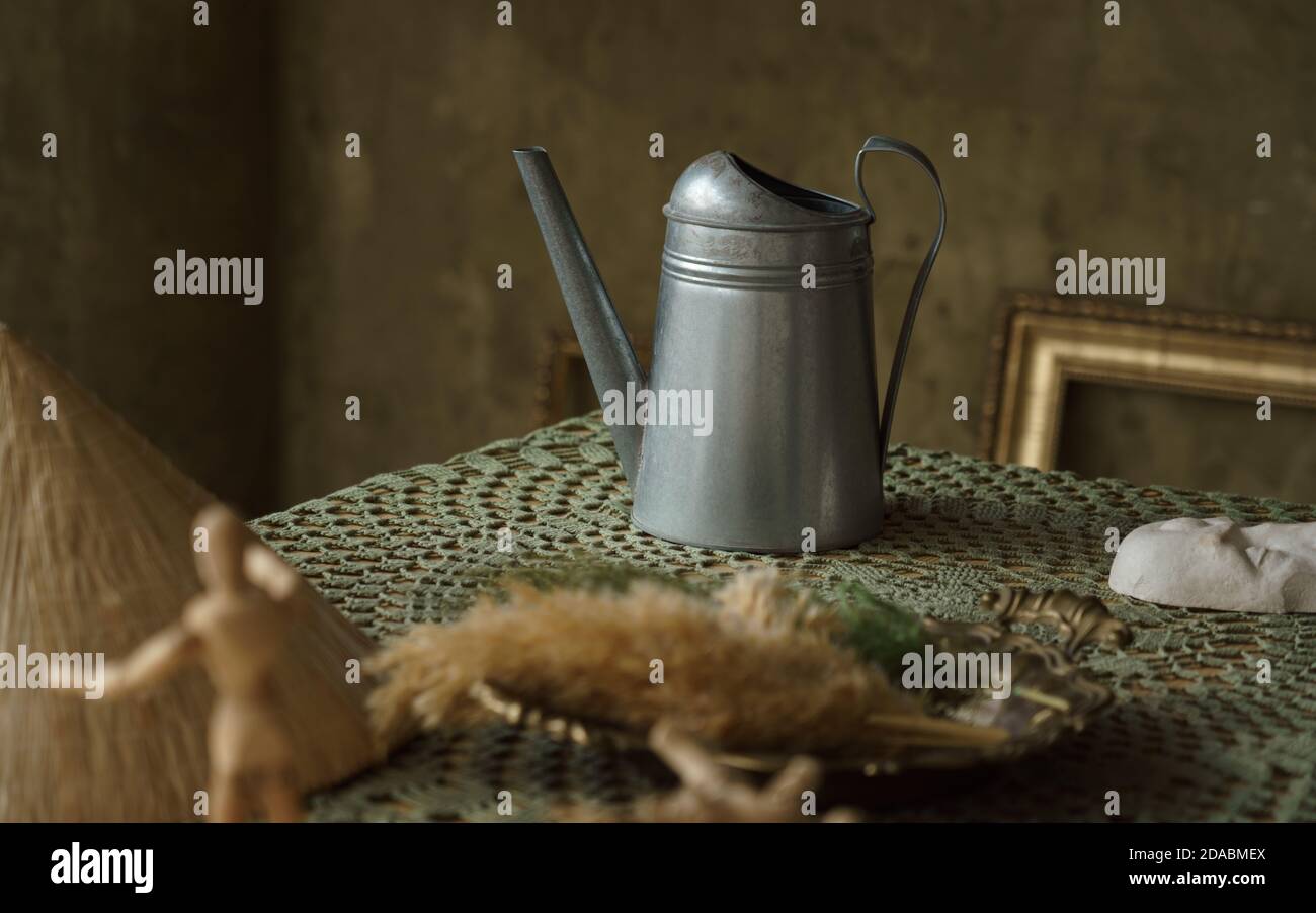 Vintage Metallkrug und auf grünem Tisch mit Kopierplatz. Malstil Zinkkkbecher auf gedecktem Tisch Stockfoto