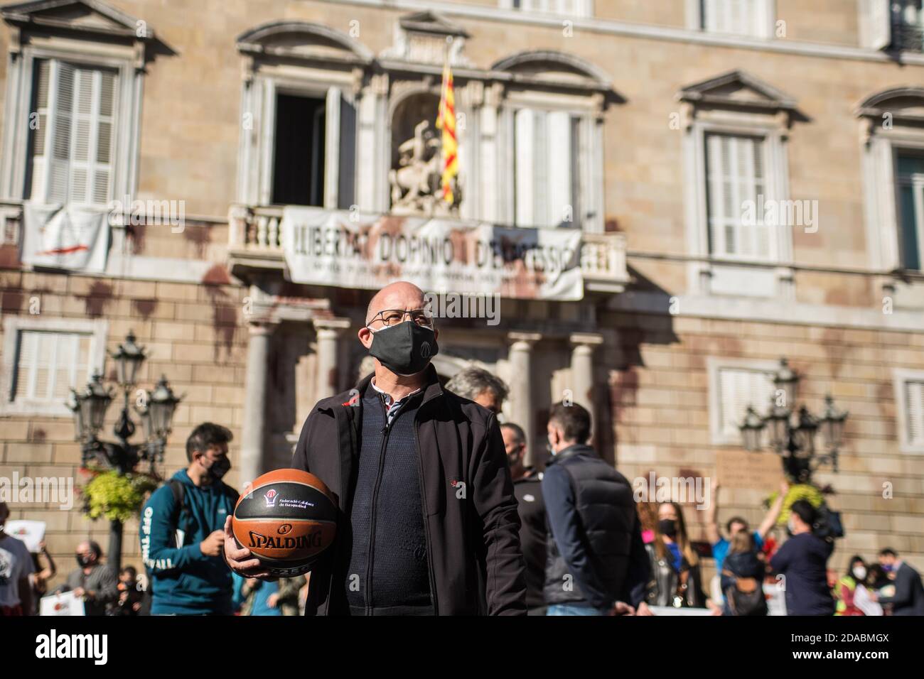 Ein Protestler mit Gesichtsmaske hält während der Demonstration einen Basketball.katalanische Sportverbände und -Organisationen haben in Barcelona demonstriert, um die Wiedereröffnung von Fitnessstudios und Sportanlagen in Katalonien zu fordern. Stockfoto