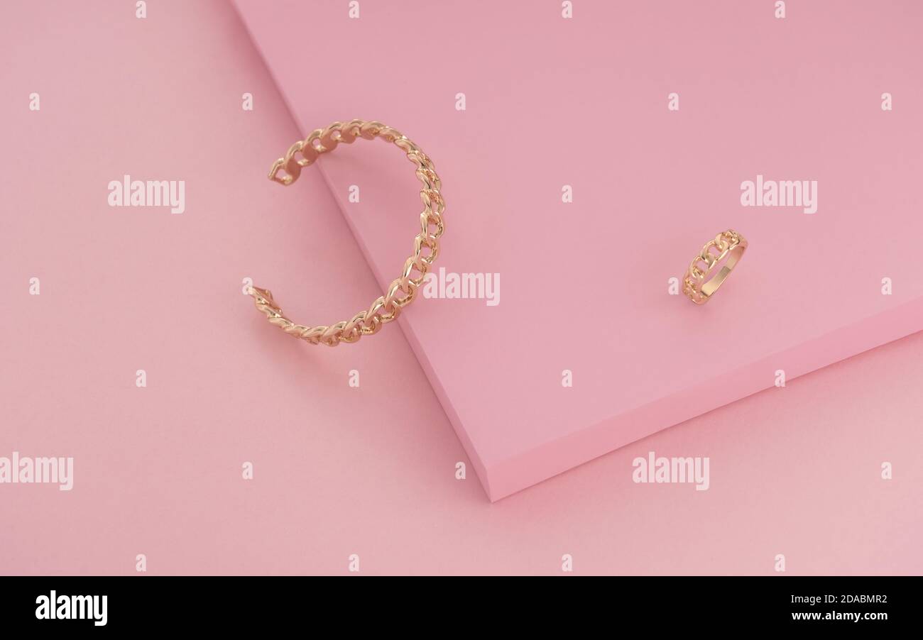Kettenform Goldener Ring und Armband auf rosa Hintergrund Stockfoto