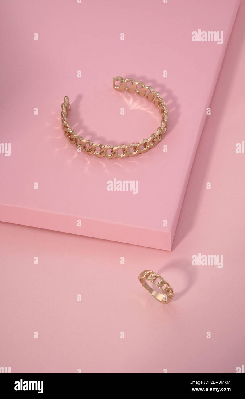 Kette Form goldenes Armband und Ring auf rosa Hintergrund Mit Kopierbereich Stockfoto