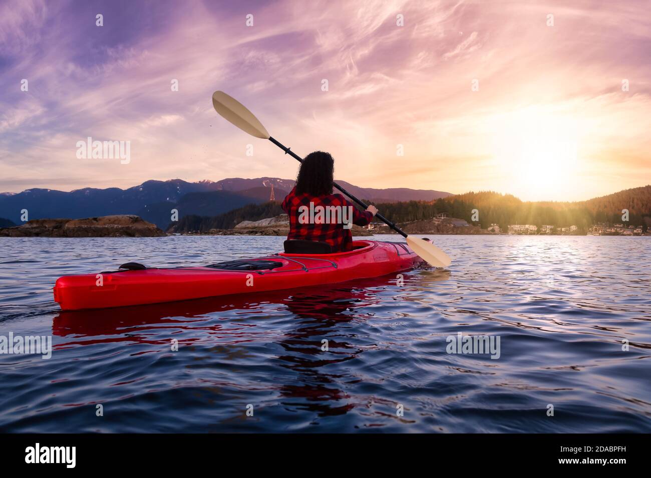 Abenteuerliches Mädchen paddelt auf einem hellen roten Kajak Stockfoto