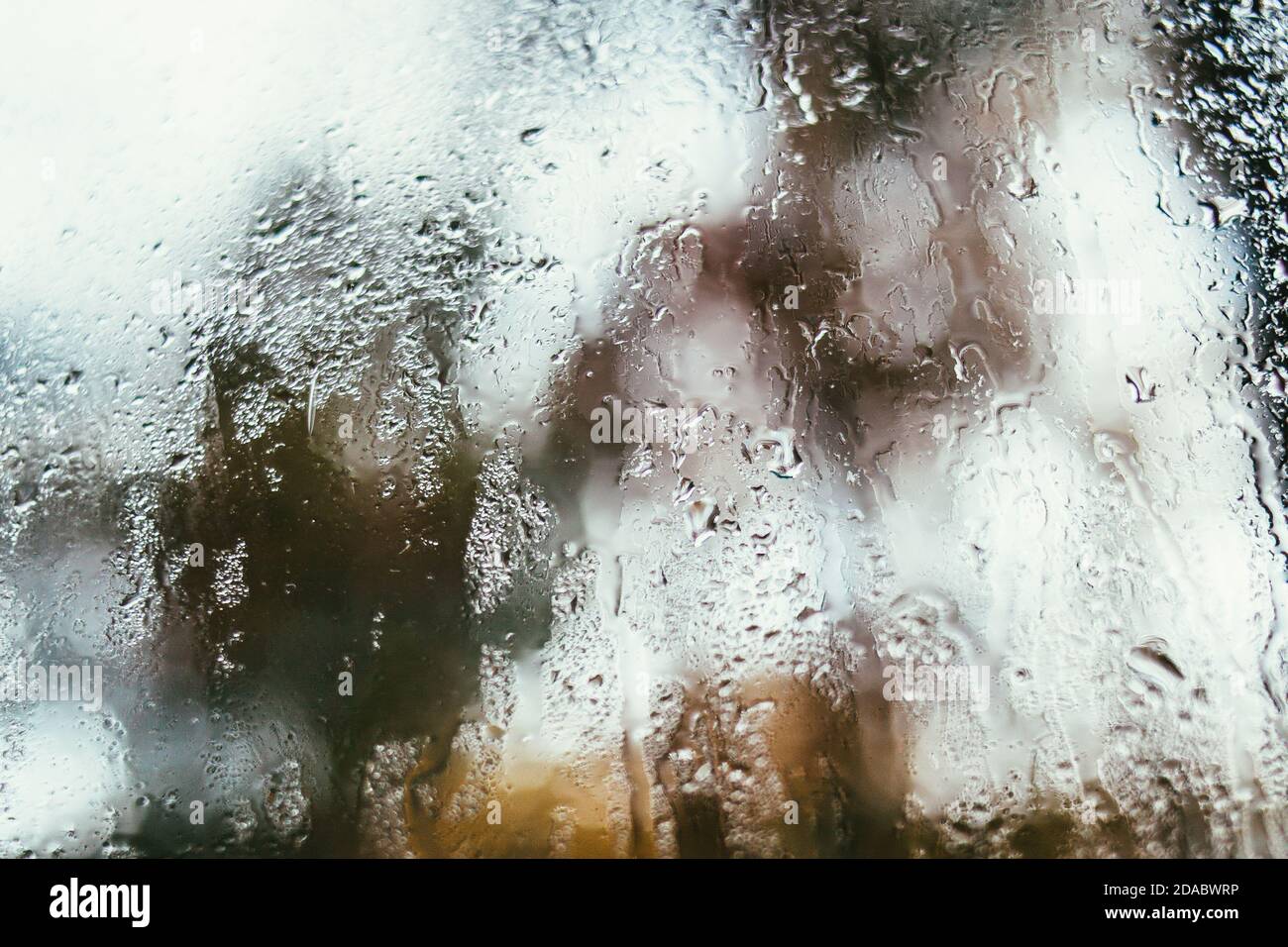 Verschwommenes Spiegelbild der Straße in einem Nebelfenster, Wassertropfen nach Regen fließen ins Glas. Wassertropfen auf dem Fenster. Konzept für Regentage. Stockfoto