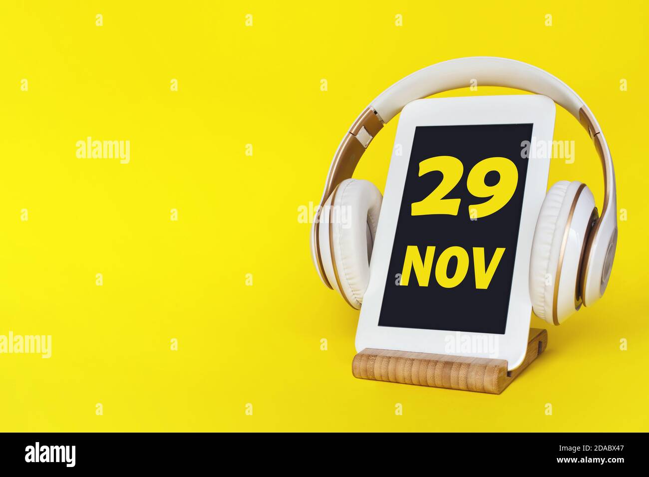 November. Tag 2 9 des Monats, Kalenderdatum. Elegante Kopfhörer und modernes Tablet auf gelbem Hintergrund. Leerzeichen für Text. Bildung, Technologie, Leben Stockfoto