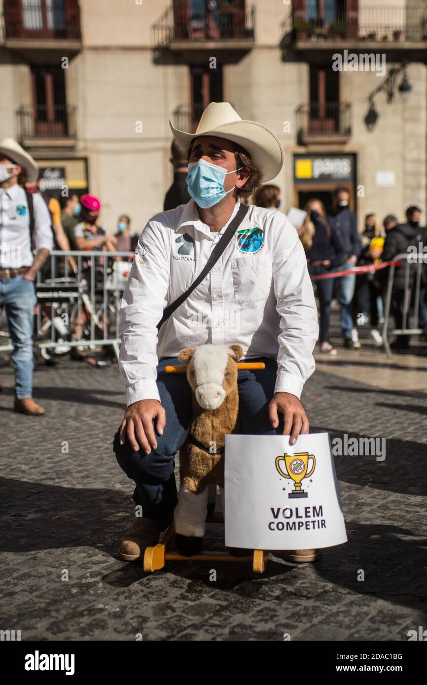 11. November 2020: Der Protestant mit Schutzmaske sitzt auf einem Spielzeug-Pferd und trägt ein Banner mit der Aufschrift: Wir wollen mitmachen. Katalanische Sportverbände und -Organisationen haben in Barcelona demonstriert, um die Wiedereröffnung von Fitnessstudios und Sportanlagen in Katalonien zu fordern.Quelle: Thiago PrudêNcio/DAX/ZUMA Wire/Alamy Live News Stockfoto