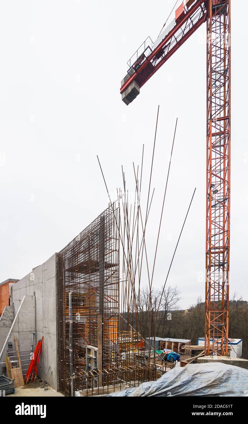 Bau von Stahlbeton Stützwand mit Stützpfeiler. Turmdrehkran. Stahlstäbe aus Stahlbeton im Gitter. Hervorstehende rostige Drähte. Stockfoto