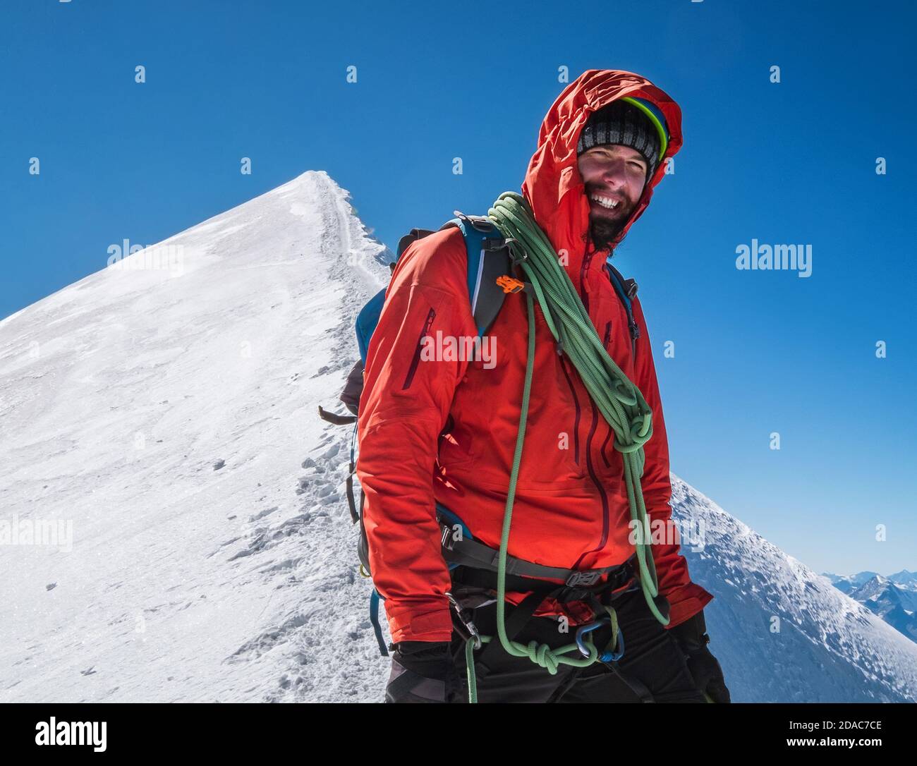 Seilteam glücklicher lächelnder Mann in einem Klettergeschirr in roter Bergsteigerkleidung Letzte Schritte vor dem Gipfel des Mont Blanc (Monte Bianco) 4808 m auf der sn Stockfoto