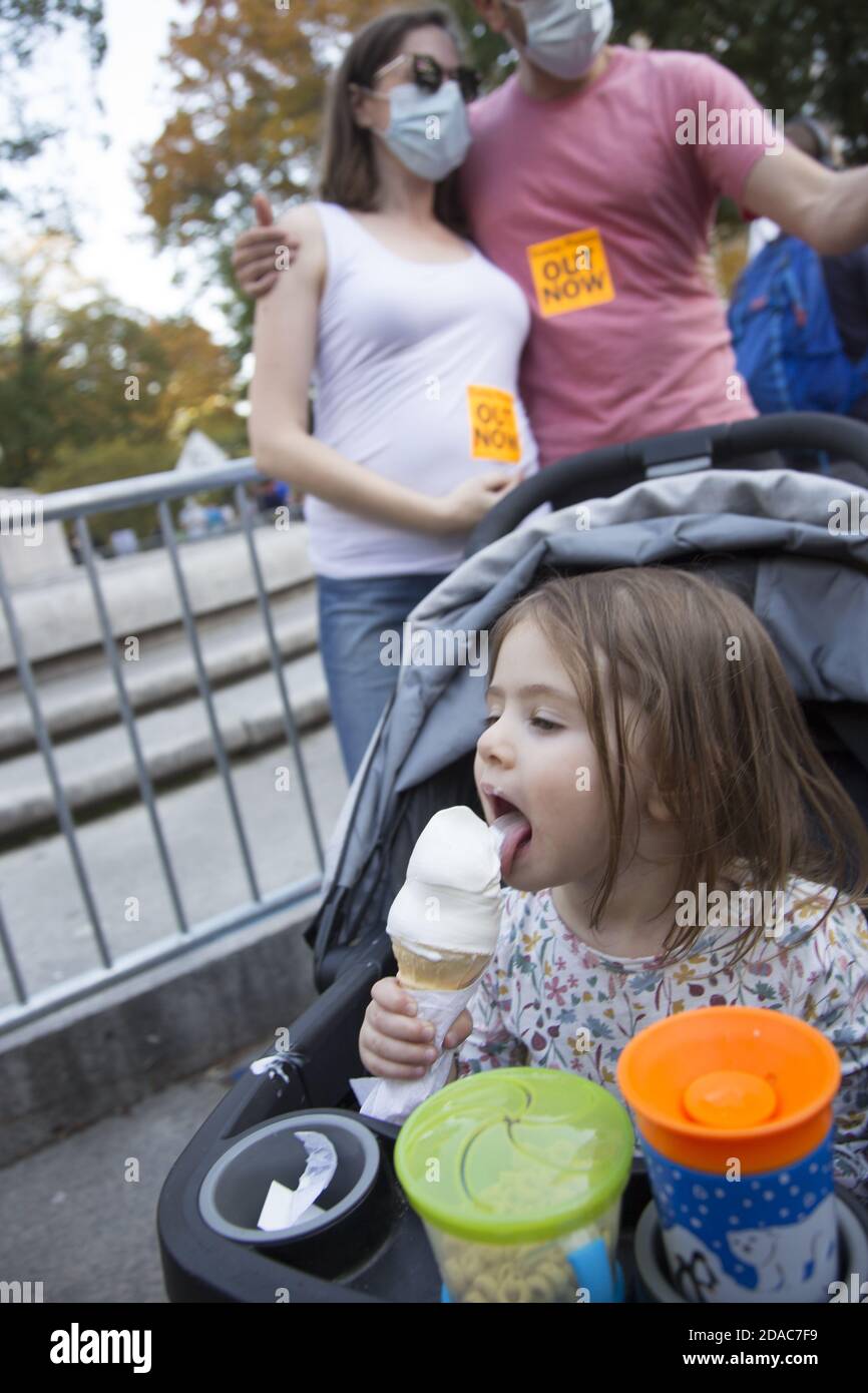 Das Kind genießt Eiscreme, während ihre Eltern den Sieg des Joe Biden-Präsidenten bei einer feierlichen Demonstration am Columbus Circle in New York City am 7. November 2020 feiern Stockfoto