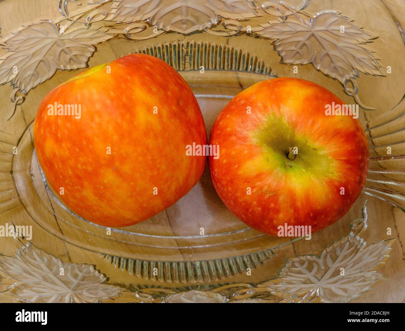 Zwei rote Äpfel in einer antiken Glasschale. Stockfoto