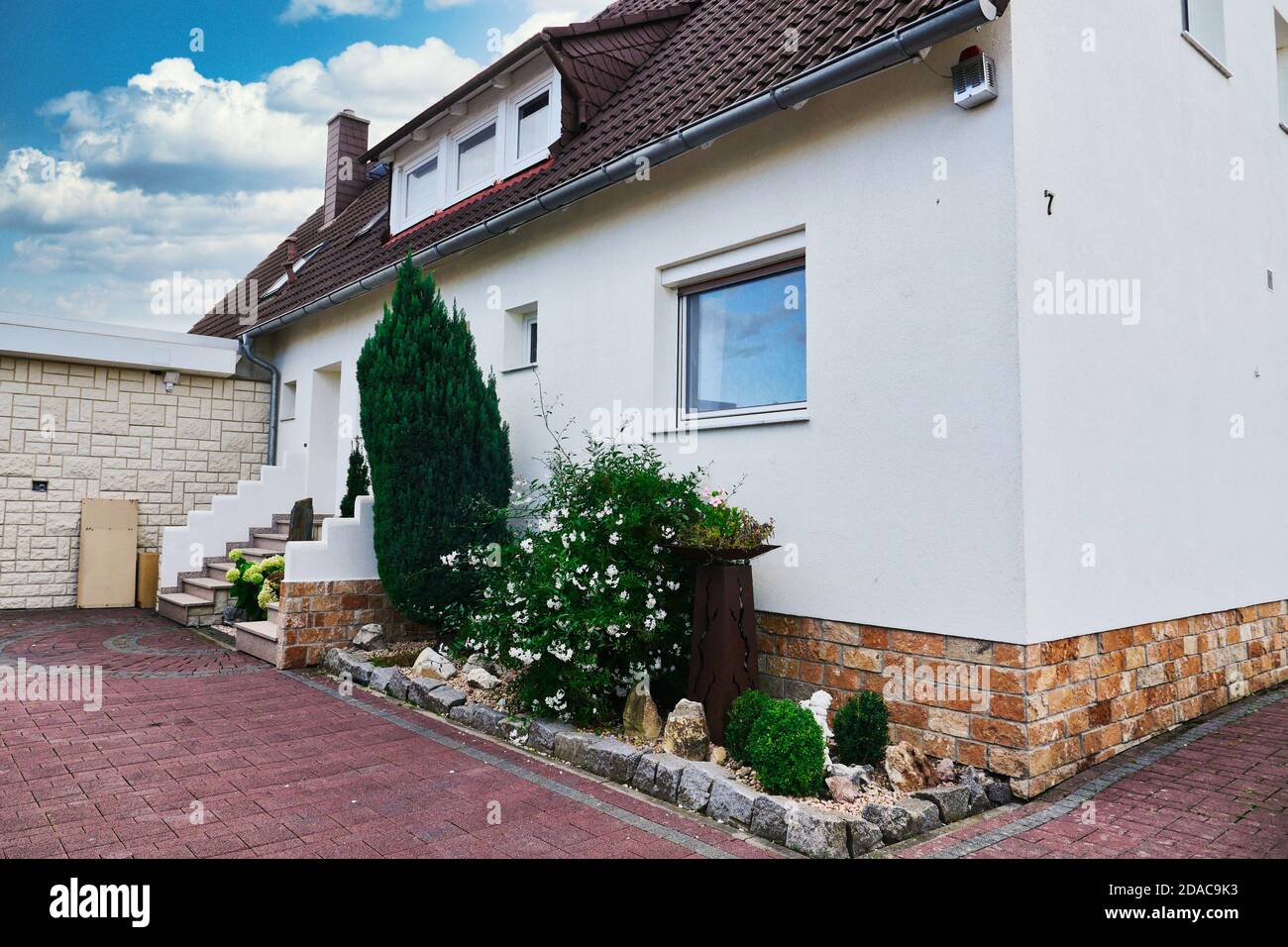 Modernes Haus mit gepflasterter Terrasse und kleinem Garten. Stockfoto