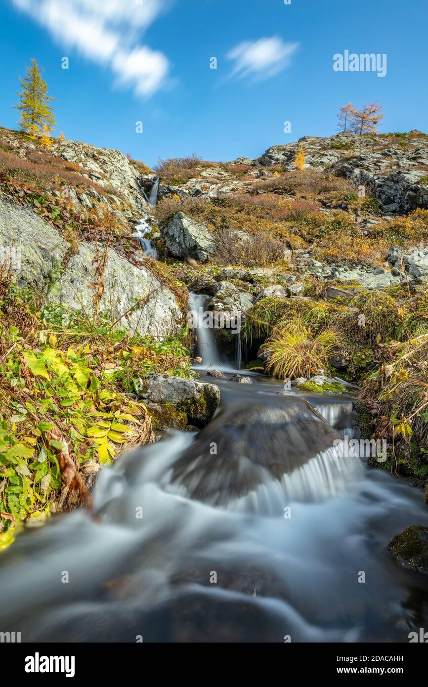 Schöne Low-Angle-Aufnahme von Wasserfall in Altai-Bergen in Sibirien, Russland. Karakolskie Seen. Glattes, seidiges Wasser und Wolken. Blauer Himmel mit Wolken A Stockfoto