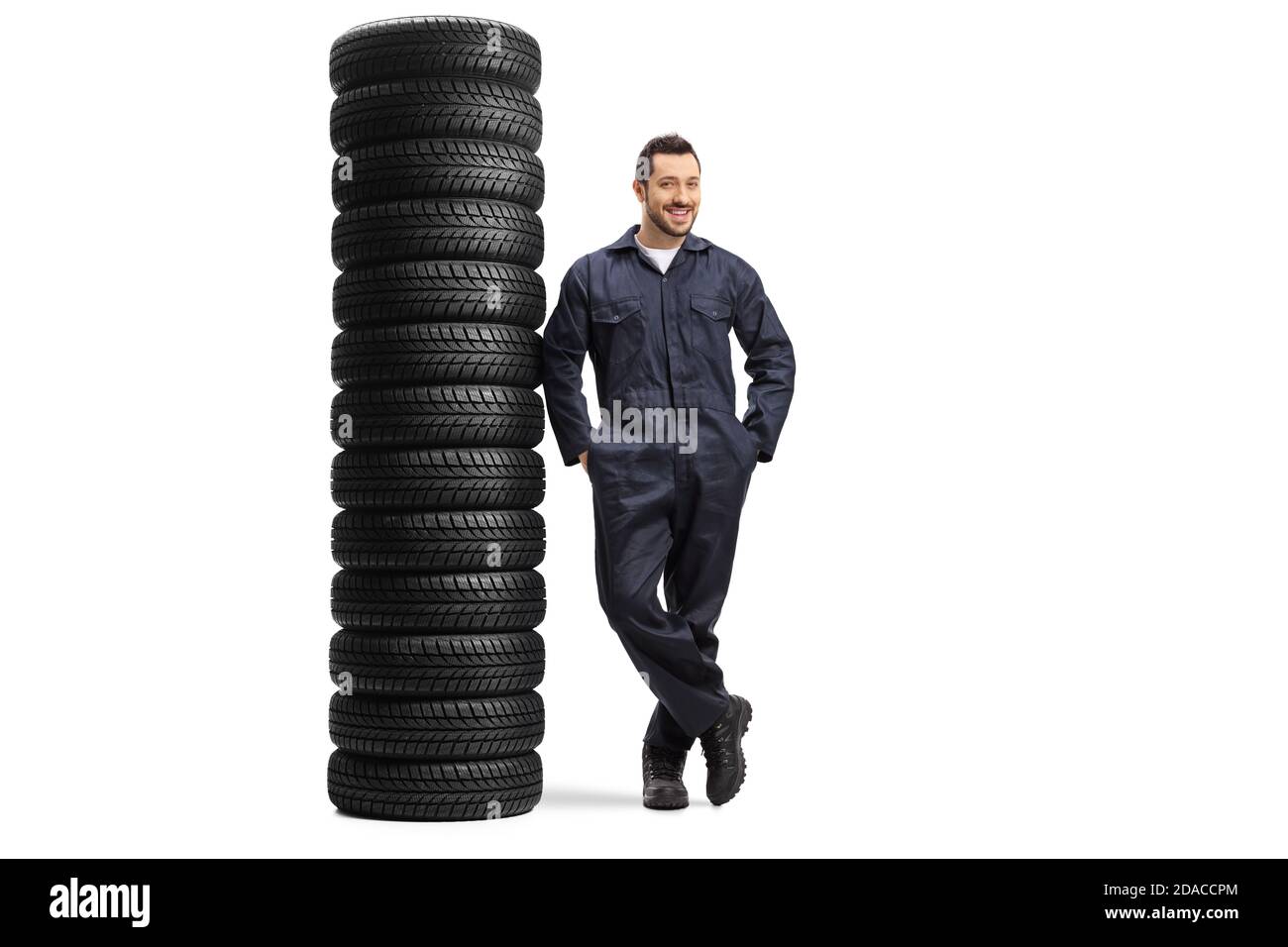 In voller Länge Porträt eines Auto-Mechaniker Arbeiter lehnt sich an Ein Haufen von vielen Autoreifen isoliert auf weißem Hintergrund Stockfoto