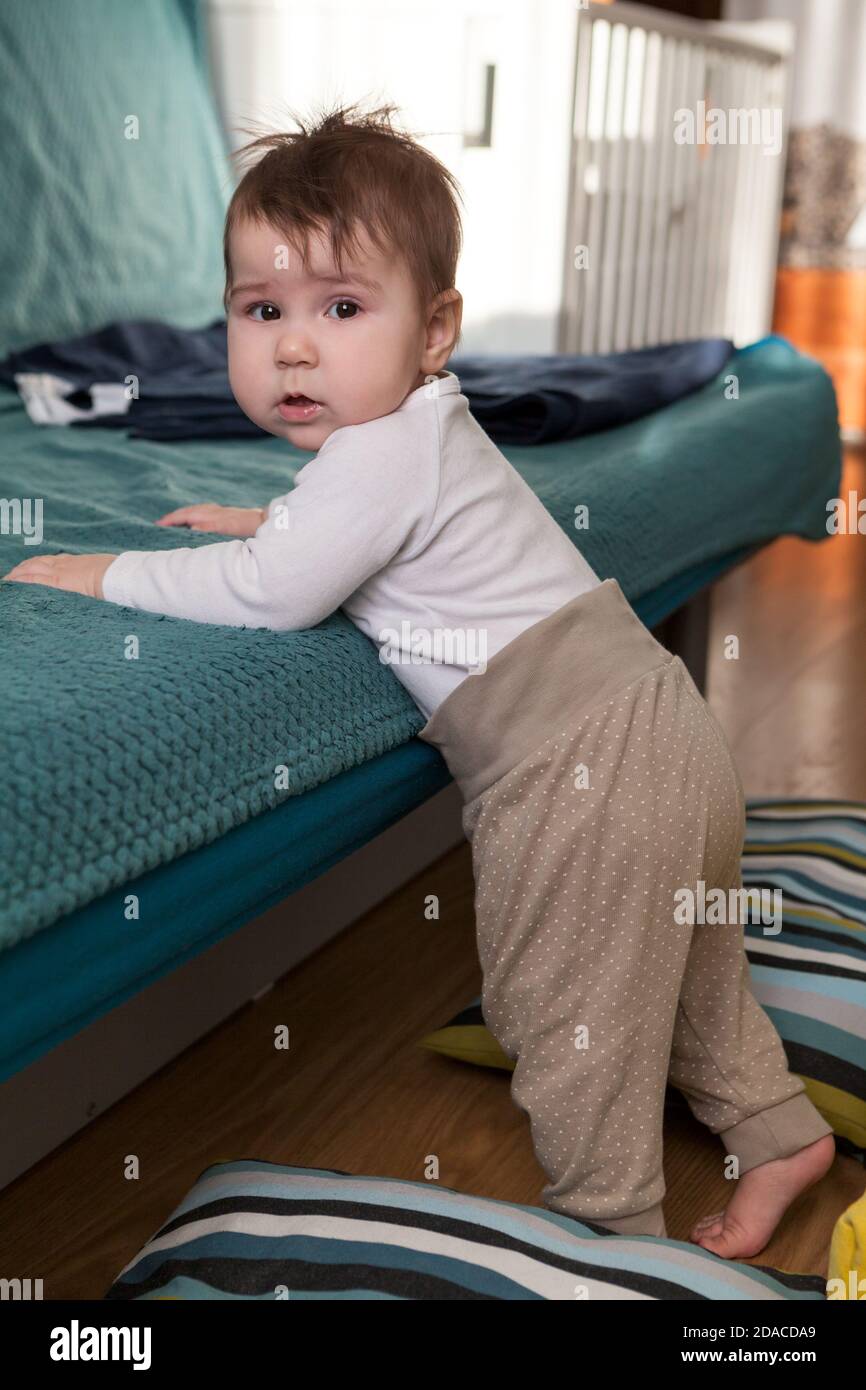 Kleinkind Kind beginnt, auf seinen Beinen stehen, hält Sofa, weiche Kissen sind um für eine Sicherheit fallen Stockfoto