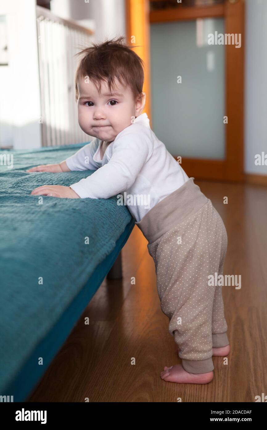 Kleinkind versucht, auf seinen Beinen zu bleiben, hält Couch im heimischen Zimmer, kaukasischen Jungen Stockfoto