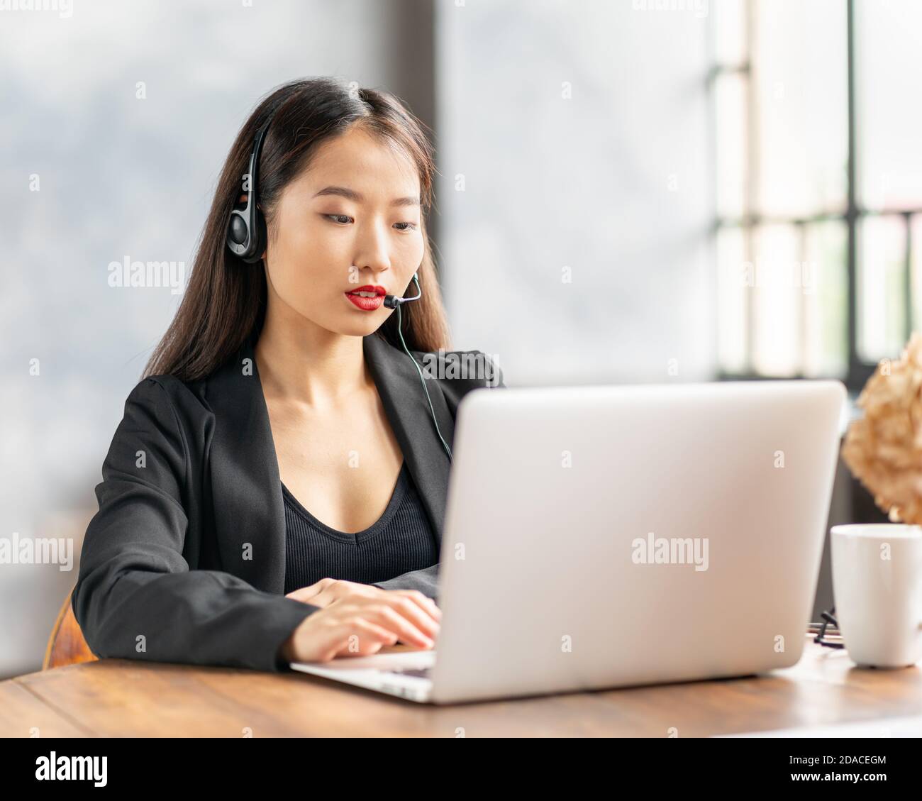Asiatische Geschäftsfrau im Headset spricht per Konferenzgespräch und Video Chatten Stockfoto