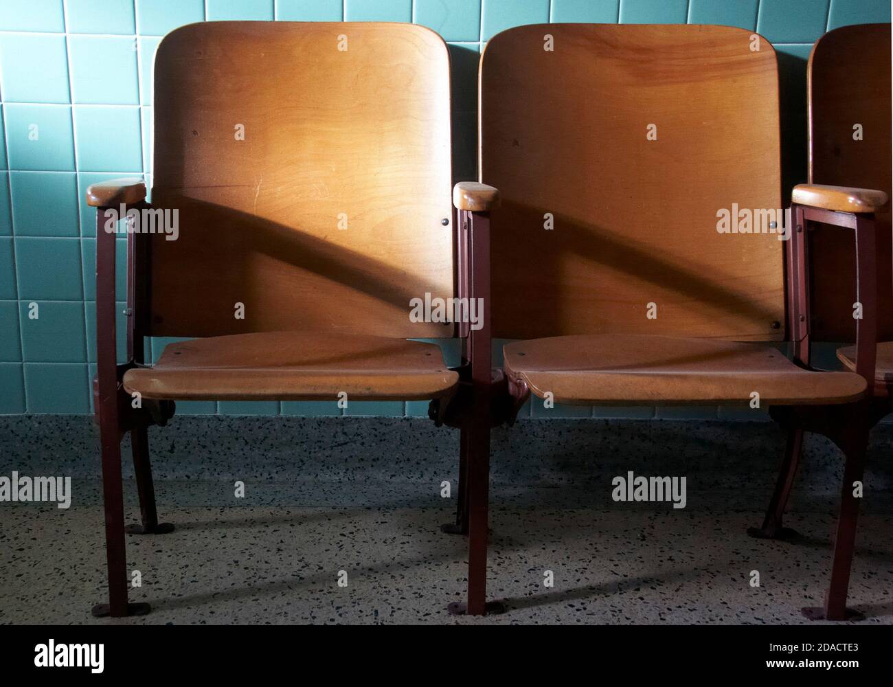 Vintage Holz Auditorium Sitze Kleinkind von türkisfarbenen Fliesenwand. Stockfoto
