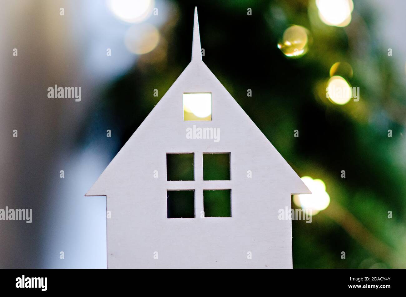 Neujahrsdekoration, Grußkarte. Weihnachtliche weiße Holzhäuser Kerzenständer auf einem grünen Hintergrund von verschwommenen hellen Girlanden von Bokeh Lichter. Fest Stockfoto