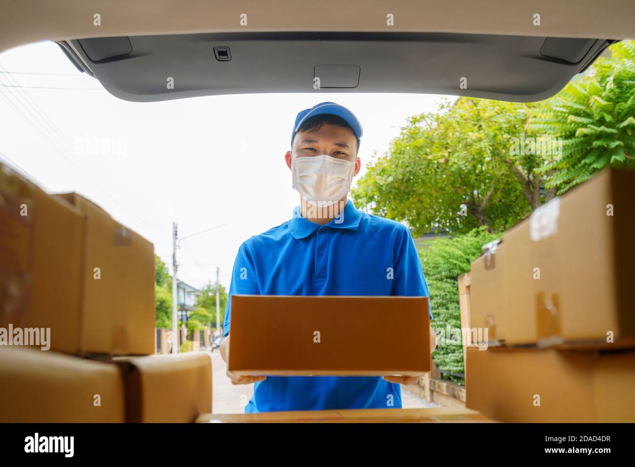 Asian Delivery man Services Kurier arbeitet mit Kartons auf van während der Coronavirus (COVID-19) Pandemie, Kurier trägt medizinische Maske und l Stockfoto