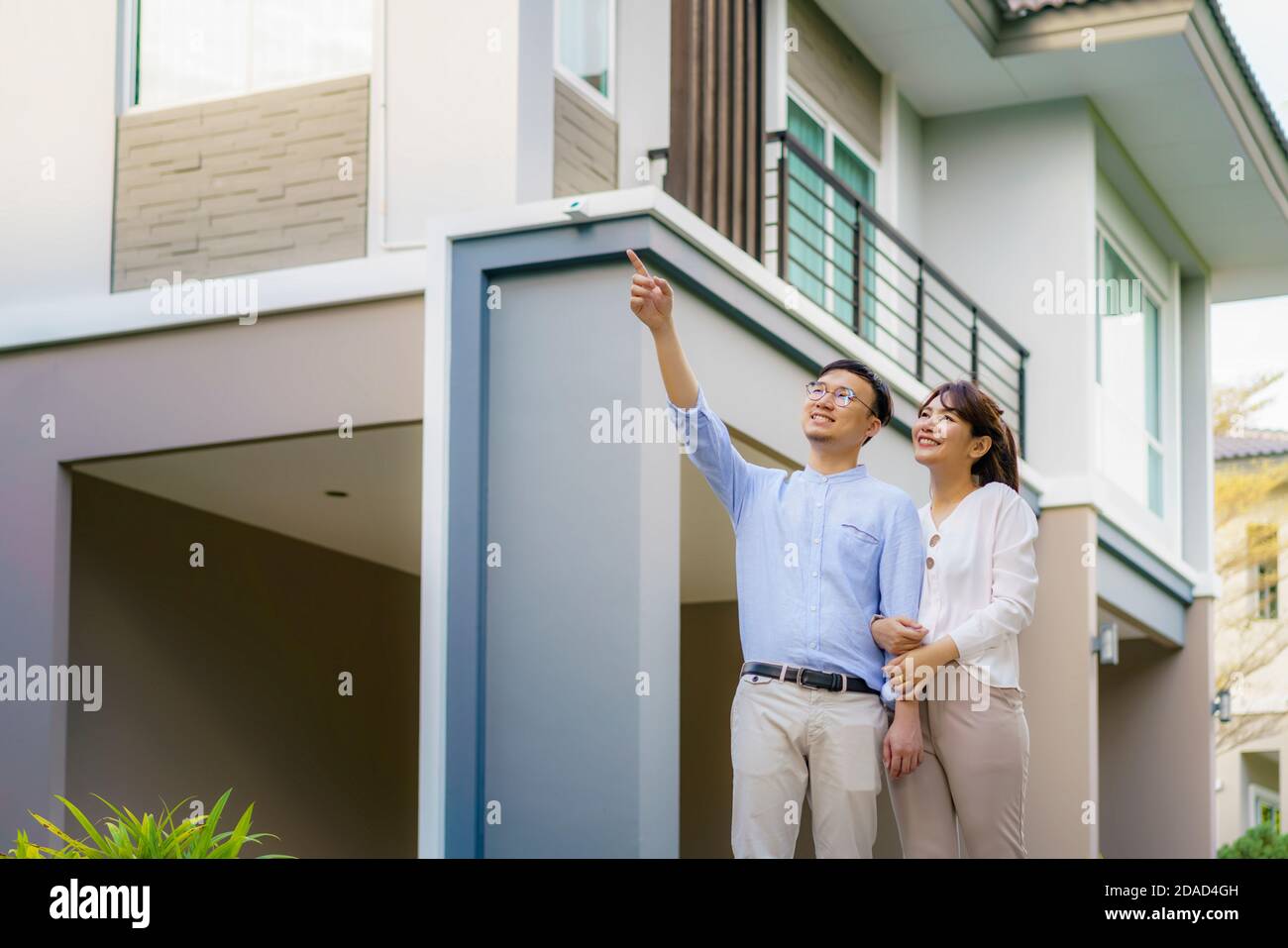 Portrait des asiatischen Paares zu Fuß umarmt und zeigt zusammen glücklich vor ihrem neuen Haus, um neues Leben zu beginnen. Familie, Alter, Heimat, echt es Stockfoto