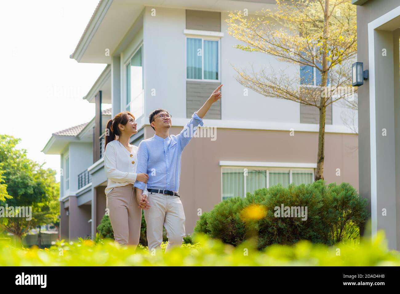 Portrait des asiatischen Paares zu Fuß umarmt und zeigt zusammen glücklich vor ihrem neuen Haus, um neues Leben zu beginnen. Familie, Alter, Heimat, echt es Stockfoto