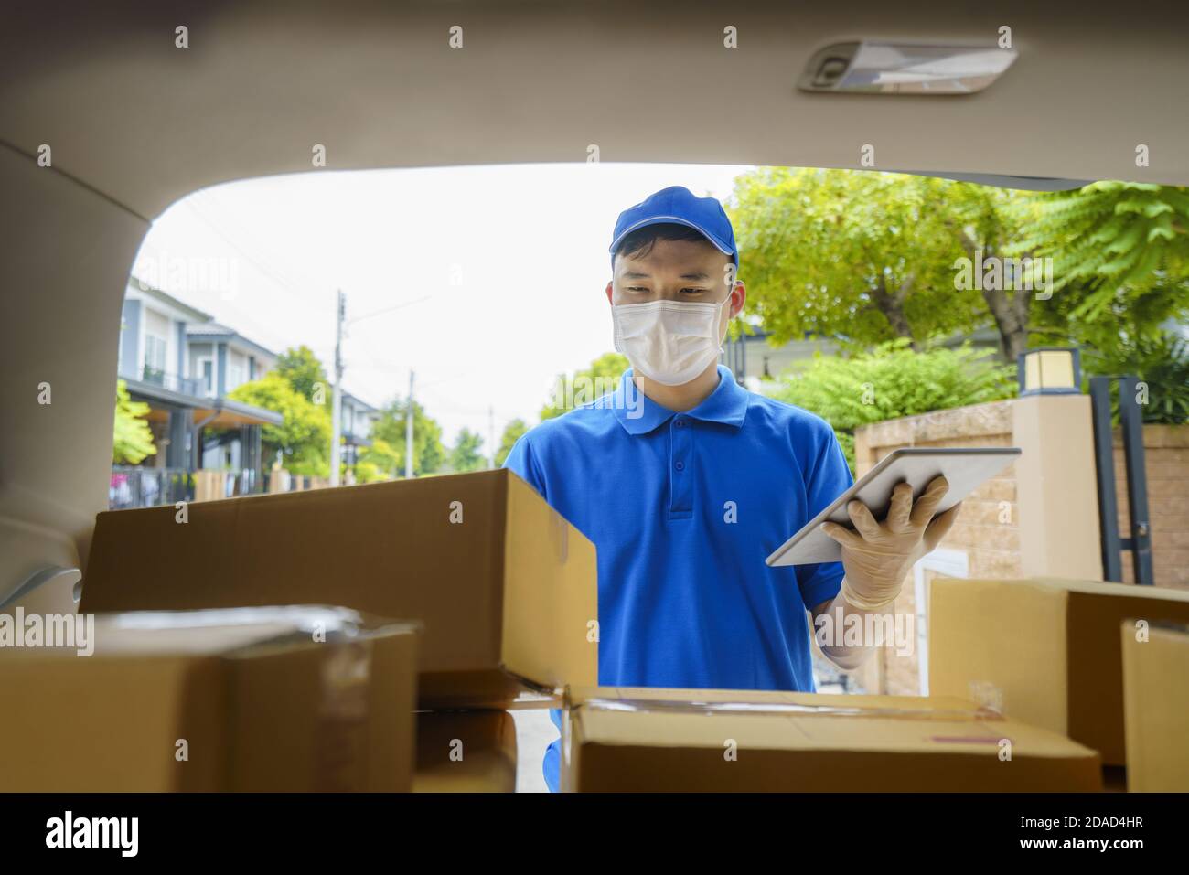 Asian Delivery man Services Kurier arbeitet mit Kartons auf van während der Coronavirus (COVID-19) Pandemie, Kurier trägt medizinische Maske und l Stockfoto