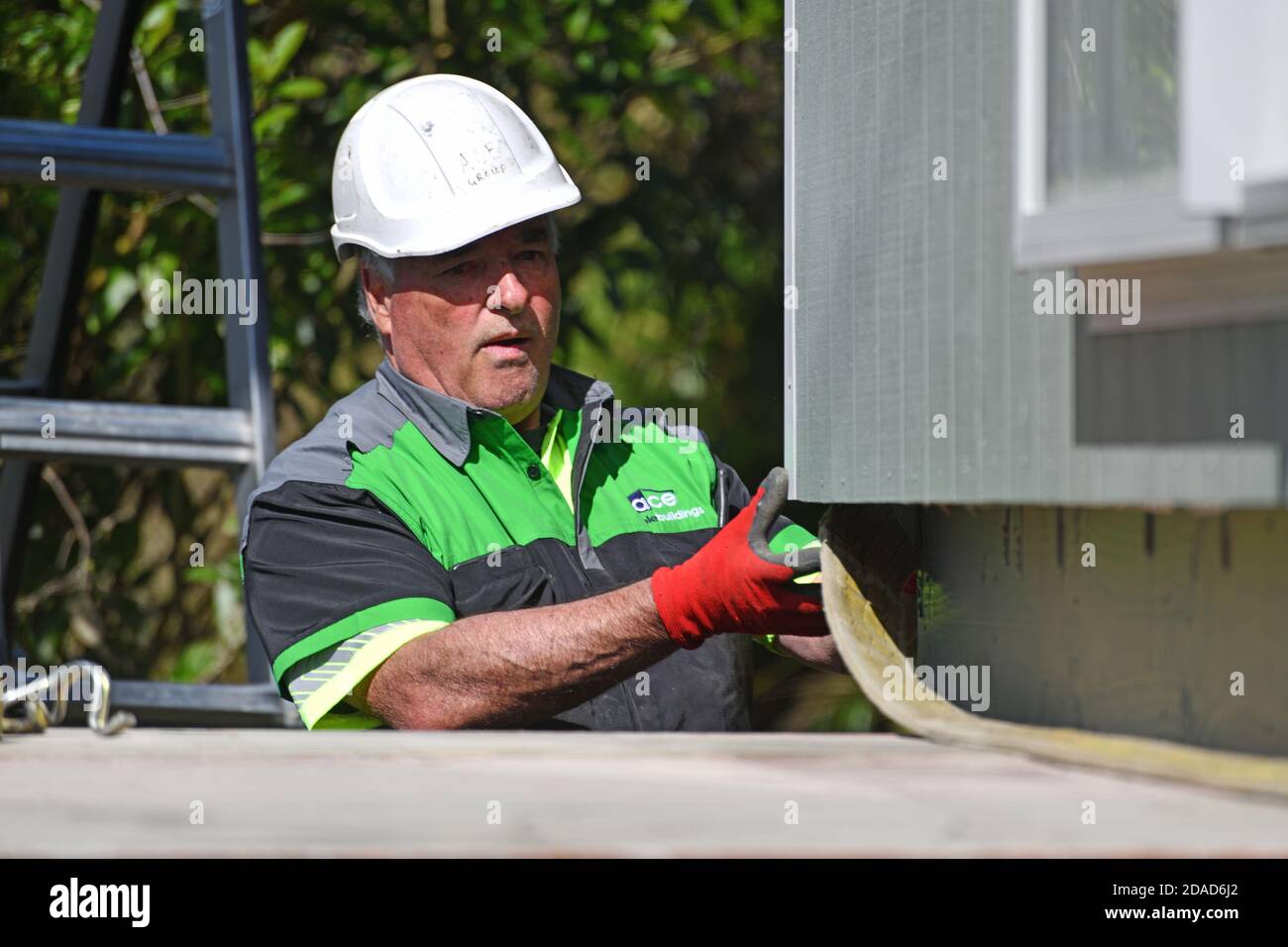 GREYMOUTH, NEUSEELAND, 21. OKTOBER 2020: Ein Kranführer arbeitet daran, ein kleines Gebäude von einem LKW auf seine Pfeiler zu heben. Stockfoto