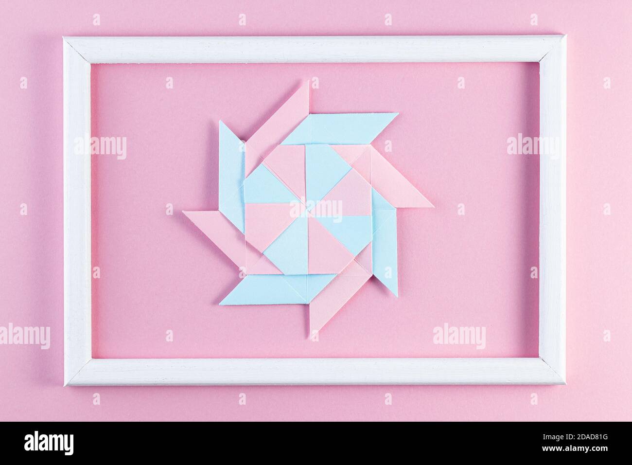 Origami-Stern. Mit quadratischen Blatt Papier und weißem Holzrahmen. Farbenfrohe Papierhandarbeiten. Stockfoto