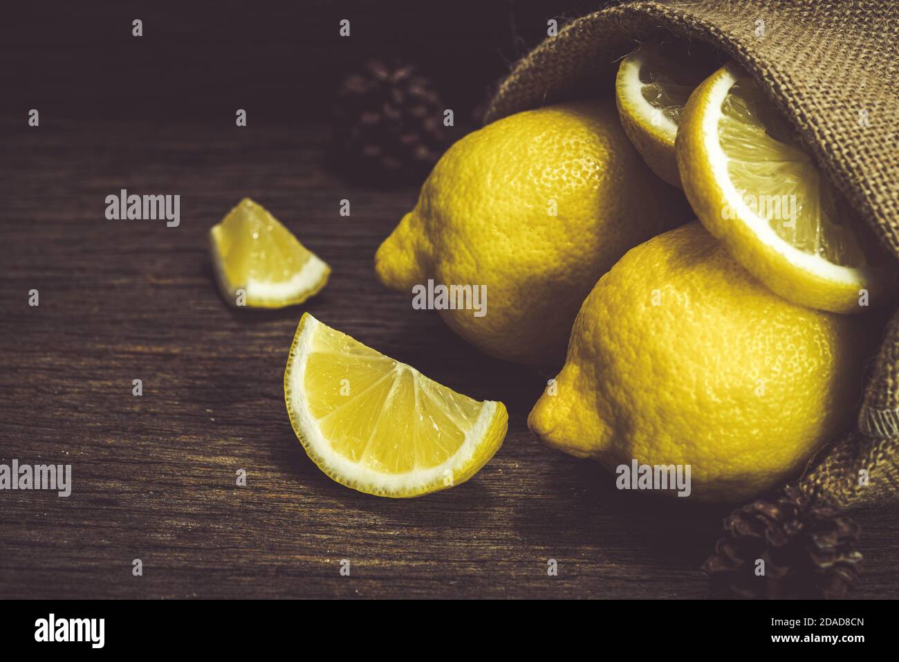 Gruppe von frischen gelben Zitronenfrüchten auf Holz Hintergrund mit Sackleinen Stockfoto